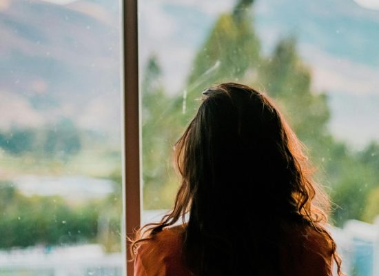 Silhouette of a woman looking out a window at a scenic mountain view in Cajamarca, Peru.